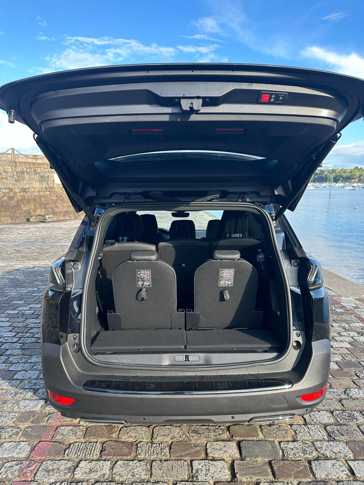 Grand coffre ouvert du Peugeot 5008 VTC avec vue sur la mer, idéal pour les transferts bagages et familles en Bretagne